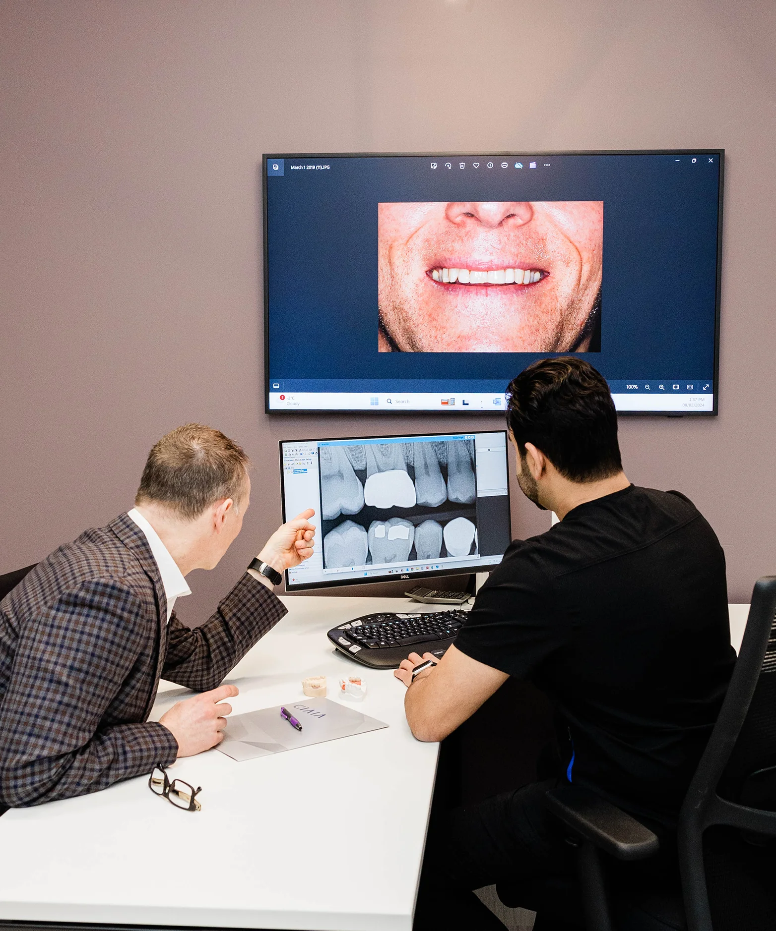 Prosthodontists reviewing a digital smile design preview with a patient on screen